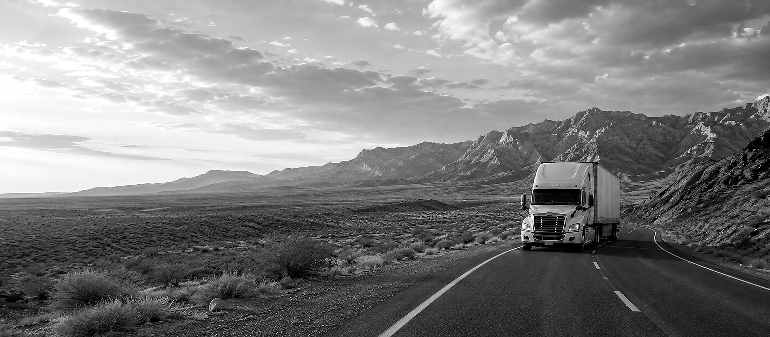 Semi truck running an open desert highway toward the mountains