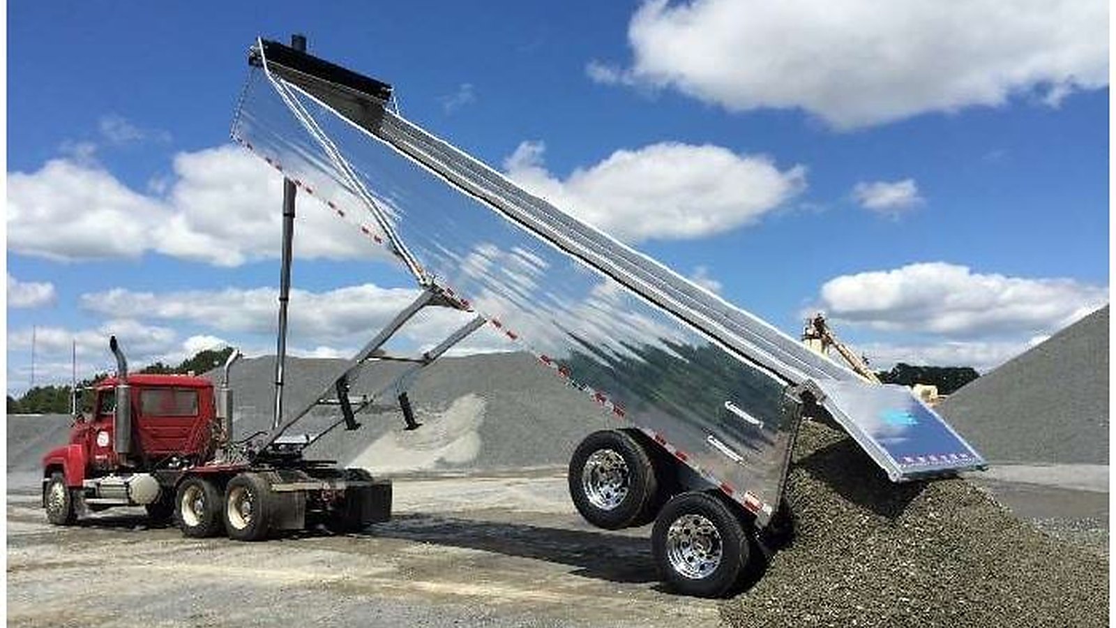 Belly dump trailer discharging aggregate on site